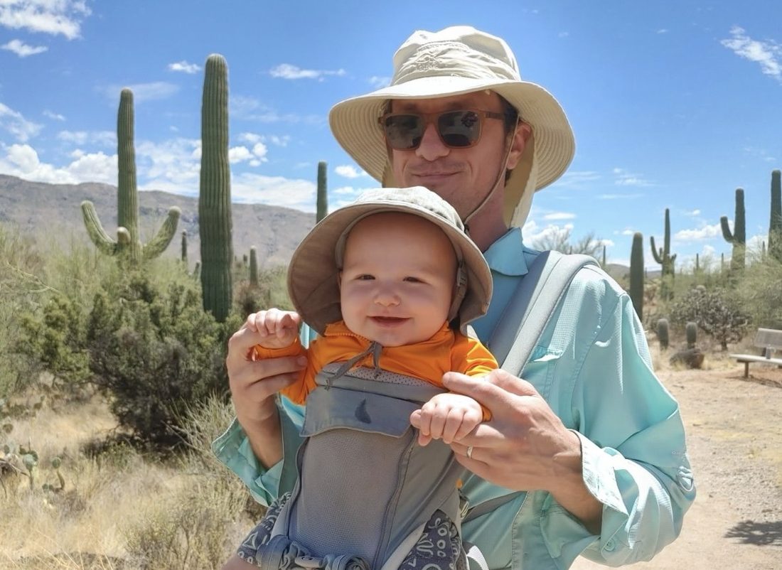Samuel Tripp hiking with his child among saguaro cactus in the Sonoran Desert outside Tucson